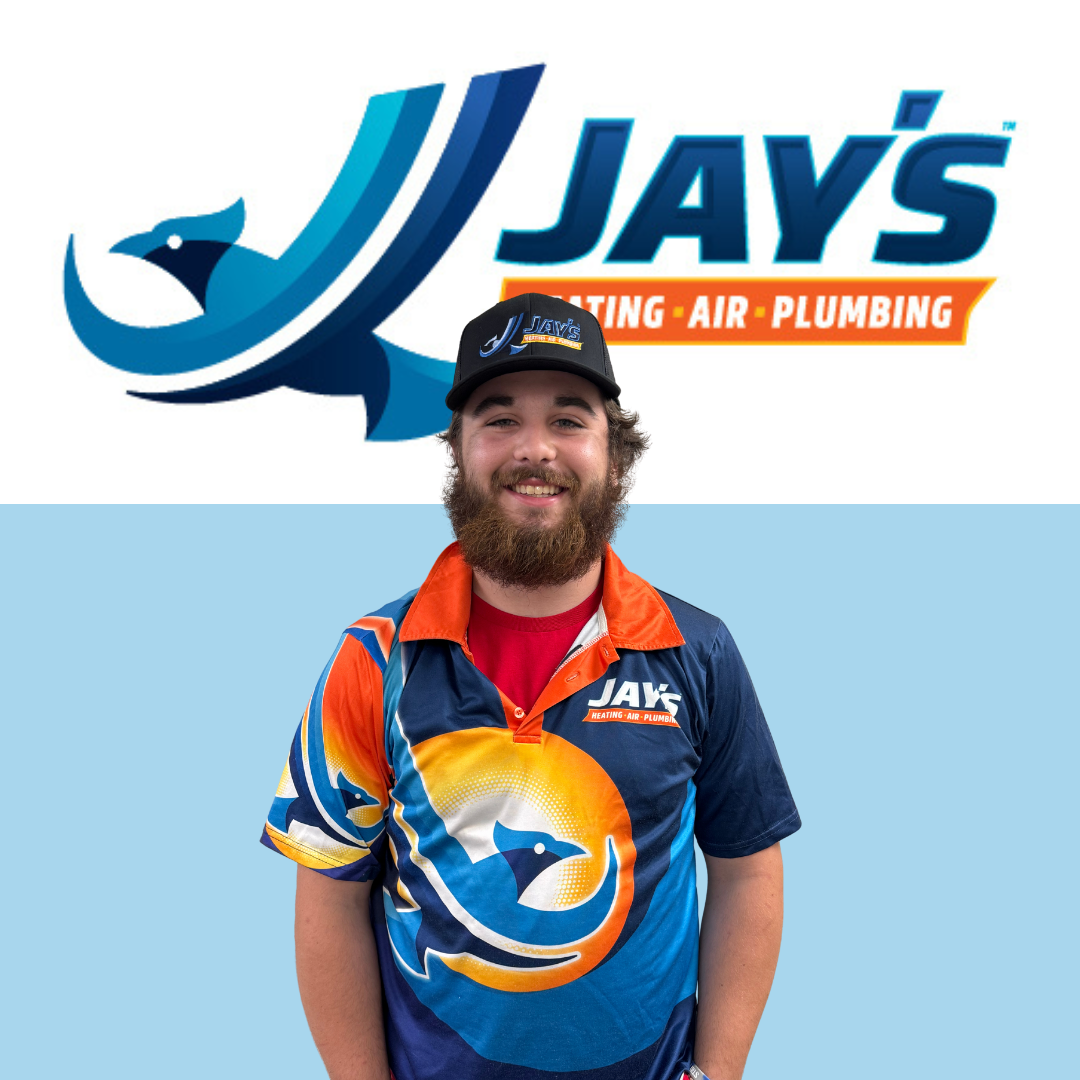 A man in a colorful Jay's Heating, Air, Plumbing uniform stands smiling in front of the company logo.