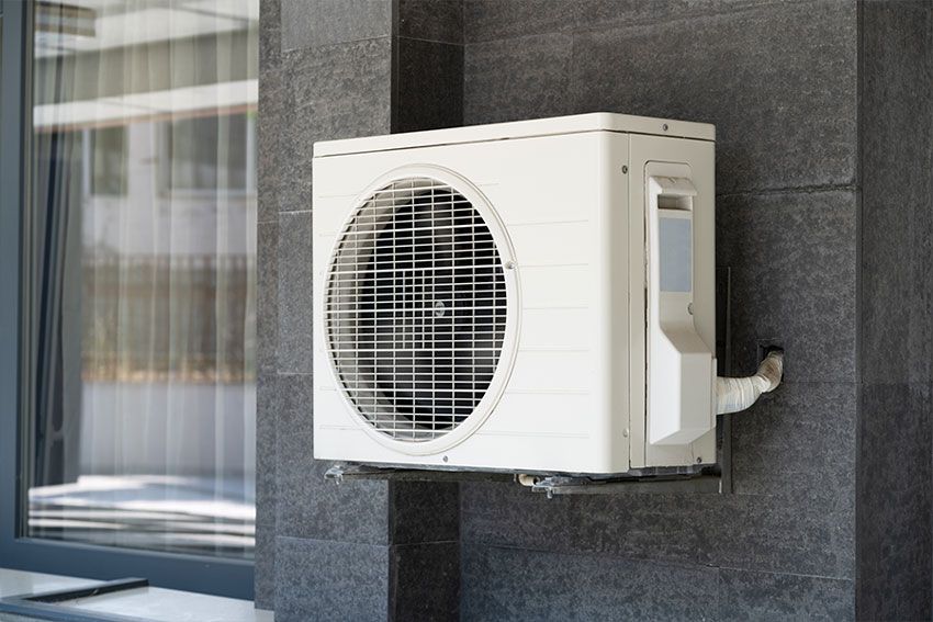 Ductless mini split condenser installed outside home